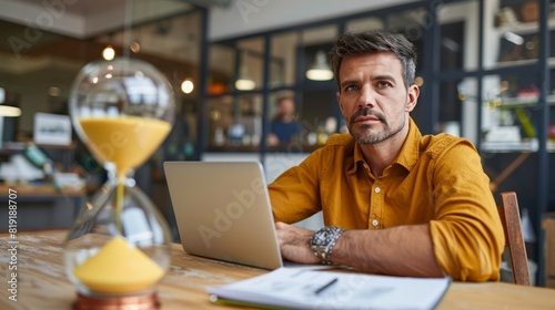 Businessman working from home with an hourglass on the table as a work deadline approaching