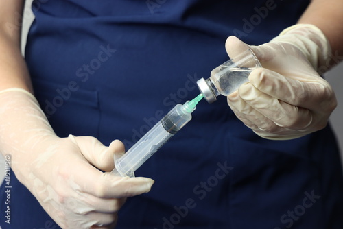 Profissional wearing gloves snorting drug from a vial with a syringe 