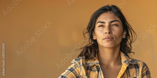 Confident young woman gazing thoughtfully in flannel shirt on ochre background