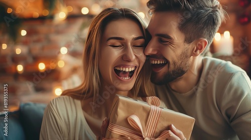 Bright emotions. Close up of young excited couple holding a present while sitting close to each