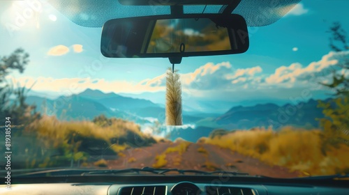 Car air freshener hanging from the rearview mirror, with a picturesque landscape visible through the windshield