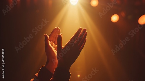 Hands clapping in warm stage light, symbolizing applause, appreciation, and celebration in a dramatic and emotional moment.