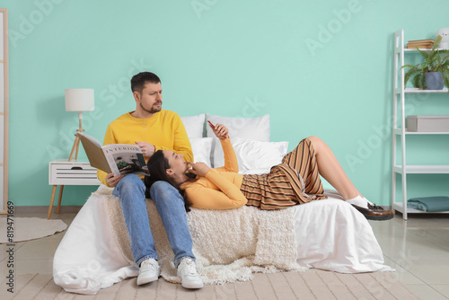 Young woman texting lover and her husband in bedroom. Cheating concept