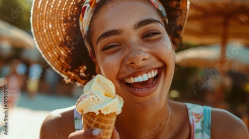 Young woman enjoying ice cream on a sunny day at the beach, wearing a straw hat and smiling gleefully.