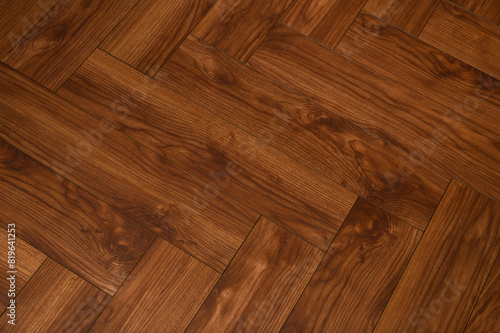 Drewniany ciemnobrązowy parkiet na podłodze z bliska, przeplatany na ukos