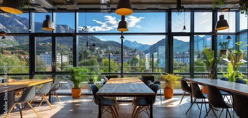 A trendy coworking space with floor-to-ceiling windows showcasing a picturesque mountain landscape