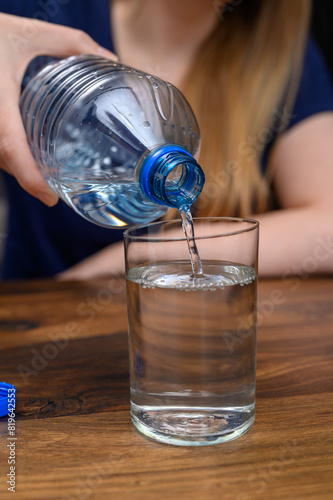 Picie wody, nalewać zimną wodę niegazowaną z plastikowej butelki do szklanki