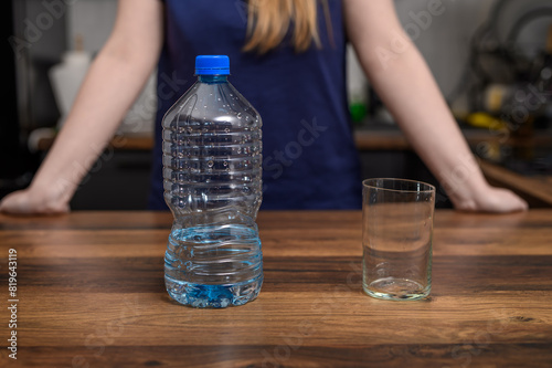 Szklanka z wodą na blacie kuchennym obok plastikowej butelki, picie wody uzupełnianie płynów w upały 