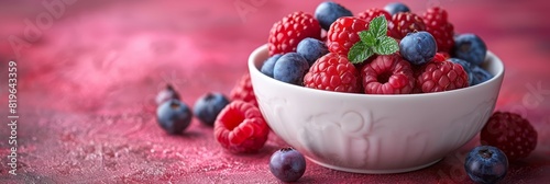 A white bowl filled with an assortment of fresh raspberries and blueberries