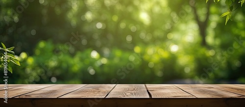 A wooden table with an unoccupied surface is set against a blurred curtain revealing a backdrop of a lush garden with green trees suitable for showcasing products or design layouts that require a copy