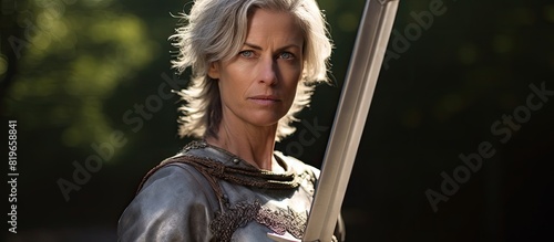 A woman in her fifties holds a sword outdoors with a copy space image