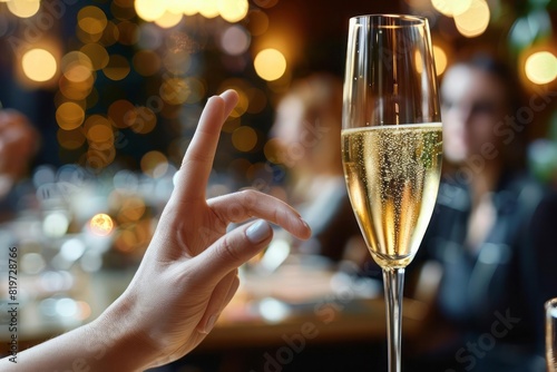 A hand gesturing no to a flute of champagne with a blurred celebration scene in the background showcasing self control