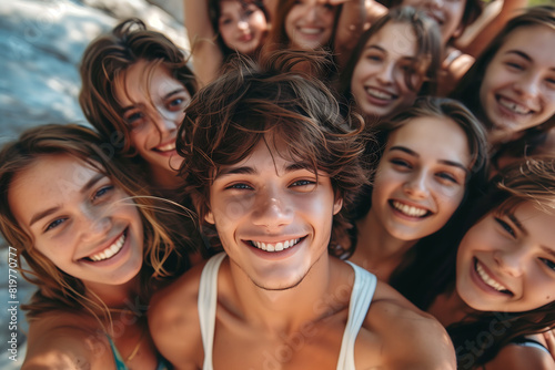 Smiling young man taking a selfie surrounded by a group of friends on vacation.