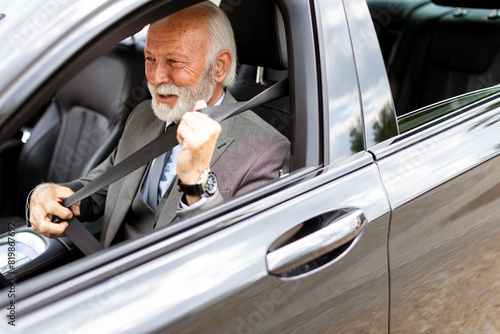 Elderly man fastening seatbelt in modern car on a sunny afternoon