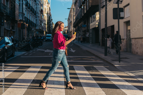 Trans woman walking in zebra pass and using cellphone at sunset. LGBT lifestyle.