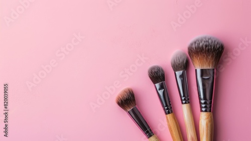 Set of five different-sized makeup brushes on pink background