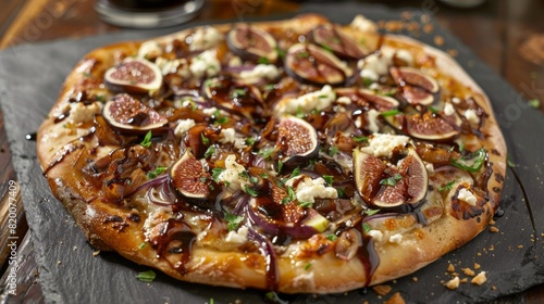 A gourmet pizza topped with figs, caramelized onions, goat cheese, and balsamic glaze, served on a slate board.