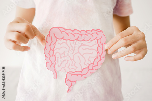 Preteen girl hands holding intestine shape, healthy bowel digestion, leaky gut, probiotic and prebiotic for gut health, preteen and teen gut health concept