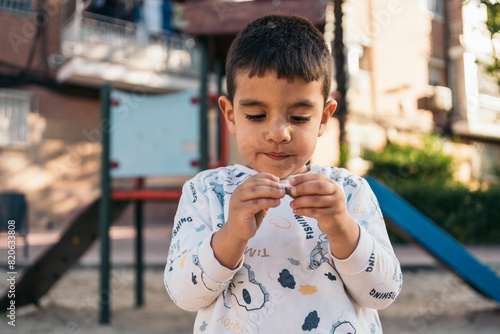 Young autistic child playing with stick outdoors. Boy focuses intently on a small stick in the playground