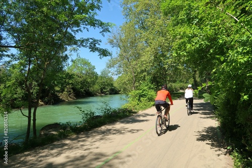 Cyclotourisme dans la campagne, au bord de la rivière Ouche à Dijon, en Côte d’Or / Bourgogne, paysage de nature avec deux cyclistes roulant sur une piste cyclable au bord de l'eau (France)