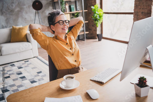 Photo of pretty retired woman have rest hands behind head dressed yellow formalwear modern workplace working home distance office