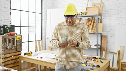 A mature man in a hardhat counts rubles in a well-lit carpentry workshop.