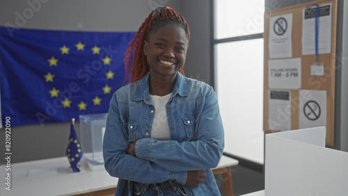 A smiling young woman with arms crossed in a room with european union flags, representing inclusivity in european electoral contexts.