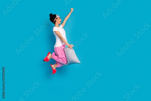 Full body portrait of pretty young woman jump fly pillow empty space wear pajama isolated on blue color background