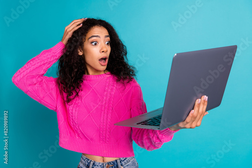 Photo portrait of attractive teen girl hold netbook amazed touch head dressed stylish pink clothes isolated on aquamarine color background