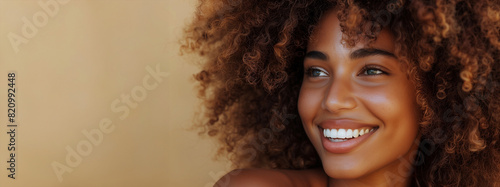 A woman with curly hair is smiling and looking at the camera. coloured woman, model, beautiful face and smile, with gorgeous big frizzy curly hair, modelling for a beauty product
