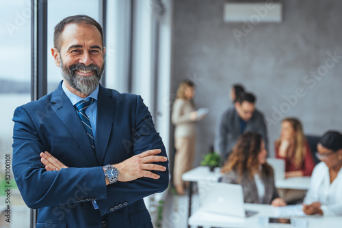 Successful business man smiling in a creative office. Portrait of happy mature man looking at camera indoor. Man with beard feeling confident. Close up face of hispanic business man smiling.