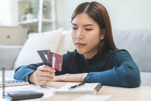 Business financial concept, stressed asian young business woman hand holding credit card for calculate accounting expense of bill, tax for payment on due deadline, trying to find money to pay debt.