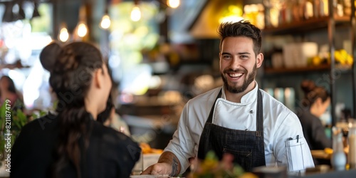 A cheerful chef in a restaurant setting talks with a customer, conveying friendliness