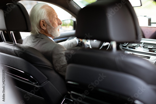 Distinguished elderly gentleman driving in a modern city on a sunny afternoon