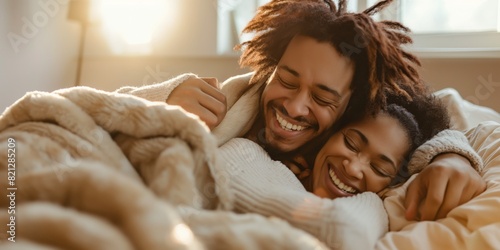 A joyful couple shares a laugh while snuggled in bed with a warm blanket