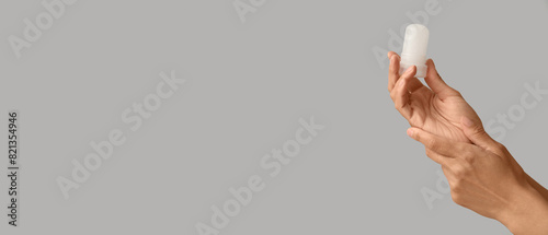 Female hands holding deodorant on grey background with space for text