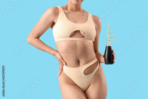 Attractive young woman in swimsuit with soda on blue background, closeup