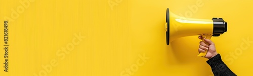 hand holding a megaphone on a yellow background.