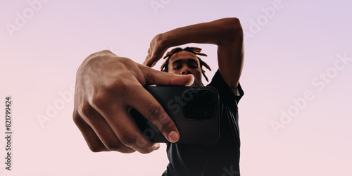Young man capturing a lifestyle pose with his selfie camera in a studio