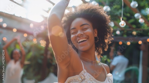 An attractive multicultural female dances and has fun on the front porch of a home. A young woman with a positive and joyful attitude relaxes at a summer garden party.