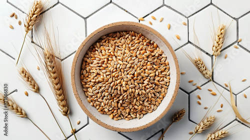 Dry barley groats in bowl on white tiled table top view