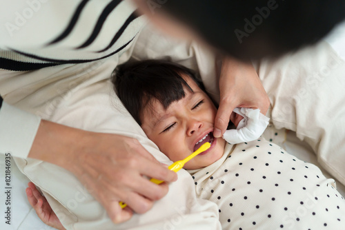 mother brushing her daughters teeth. crying baby with tooth brush