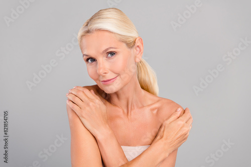 Portrait of happy calm peaceful pensioner woman hug herself enjoy soft fresh skin peeling scrub isolated on gray color background