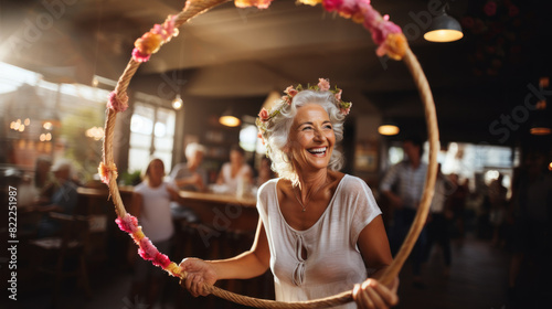 A senior woman full of vitality plays with a hula hoop, adorned with a floral wreath, in a festive atmosphere