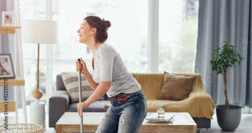 Happy woman, singing and cleaning with mop on floor for housekeeping or tidying in living room at home. Female person, maid or cleaner enjoying fun chores for dirt, bacteria or germ removal at house