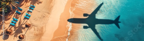 Aerial view of an airplane shadow flying over the beach with blue water and palm trees There are also some sunbeds on the sandbeach at sunrise