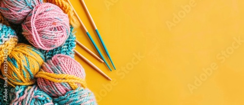Pair of knitting needles with yarn with clear copyspace on yellow background