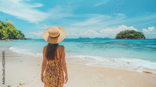 Back view young tourist woman in summer dress and hat standing on beautiful sandy beach