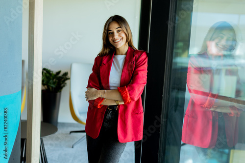 Confident young professional in red blazer smiling at modern office environment