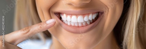 The woman smiles and points her finger at her snow-white healthy teeth. The banner